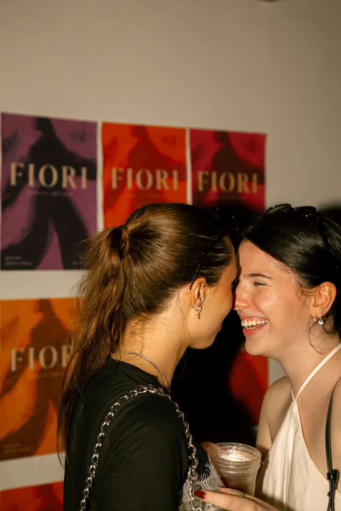 Duas amigas rindo diante dos cartazes Fiori